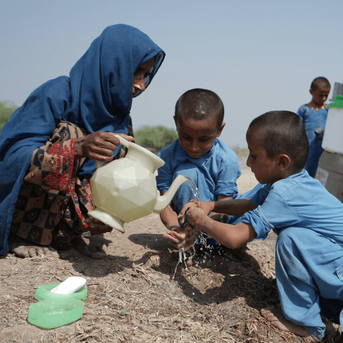 Balochistan province, Pakistan: Imam washes her children’s hands with floodwater. Photo: Ingenious Captures/Oxfam.