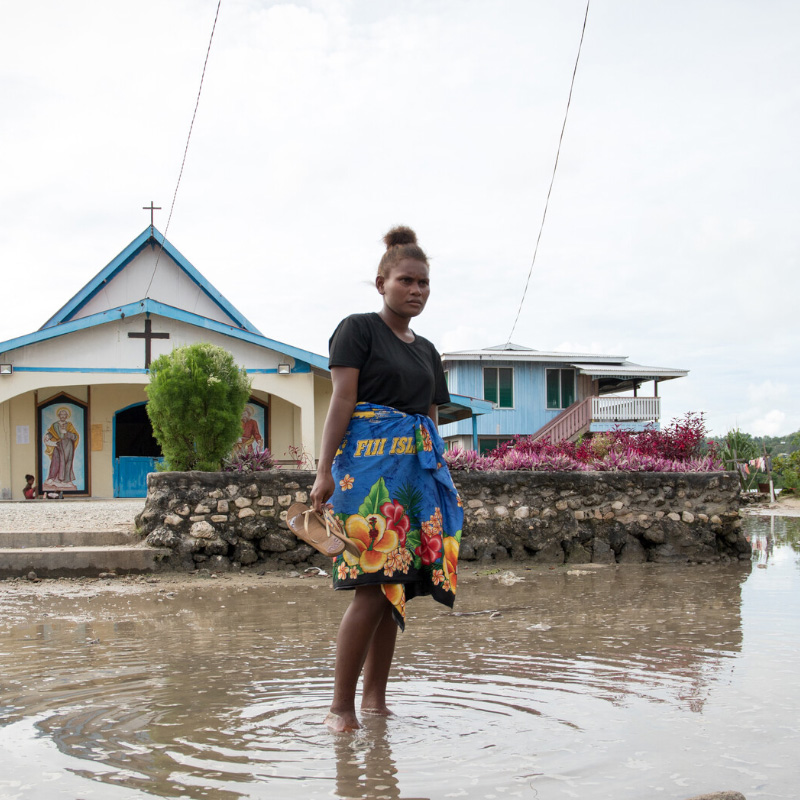 Portrait of Grace a 19 year old student standing in a flooded street outside neat a church in Lilisiana, Malaita Province, Solomon Islands.